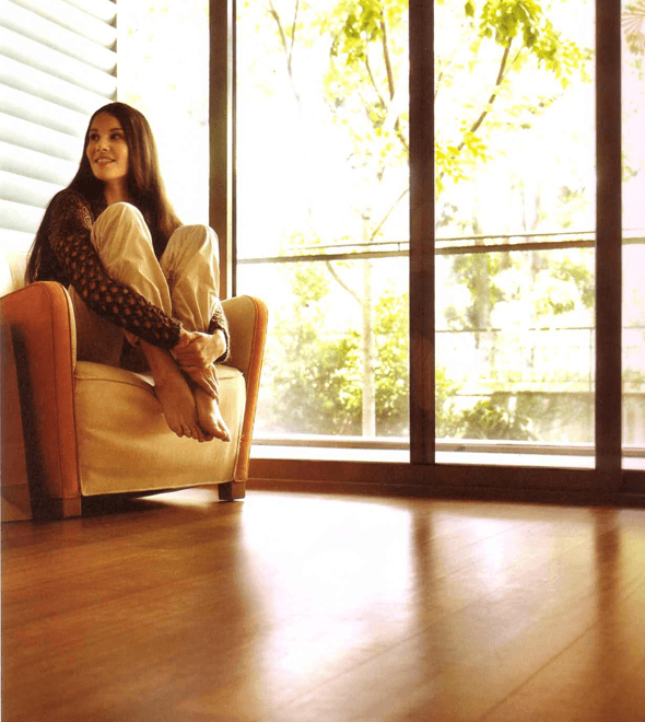 A homeowner relaxing in a sunlit room with new hardwood floors