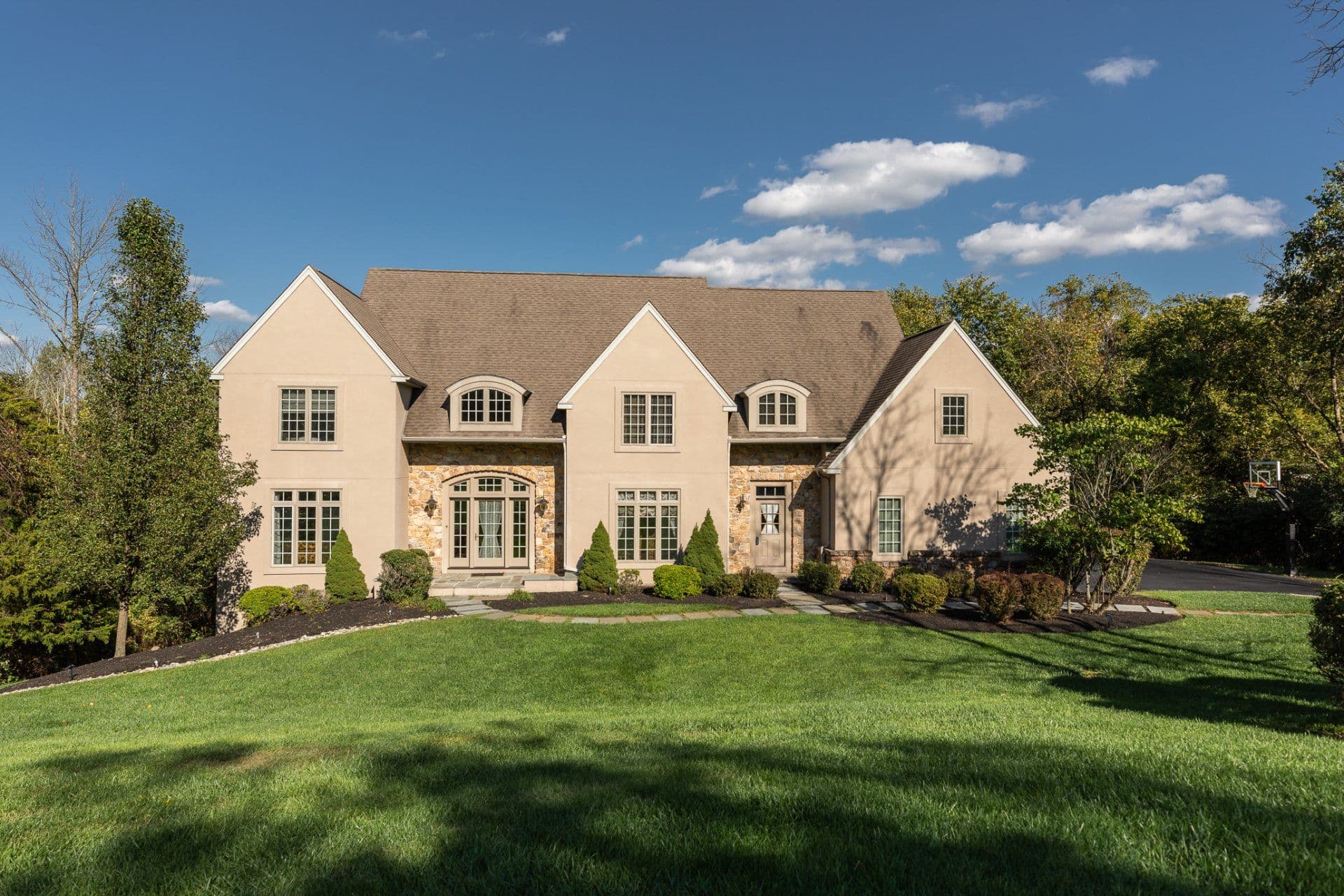 A fully restored stone-front home on a green lawn under a blue sky